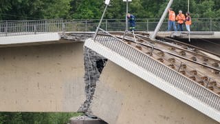 Mitarbeiter vom THW arbeiten neben einem Teil der eingestürzten Carolabrücke