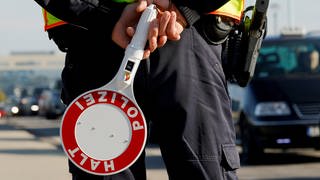 Ein Bundespolizist steht an der deutsch-polnischen Grenze mit einer Polizeikelle.