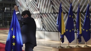 Ein Mann stellt vor dem EU-Westbalkan-Gipfel die EU-Flagge in Brüssel auf