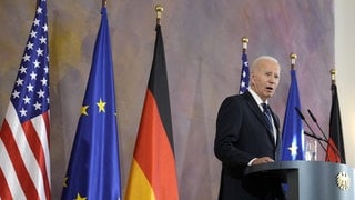 Joe Biden spricht im Schloss Bellevue, hinter ihm stehen die Flaggen der USA, der EU und von Deutschland.