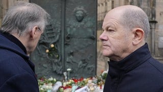 Olaf Scholz (rechts) und Reiner Haseloff vor Trauerblumen in Magdeburg