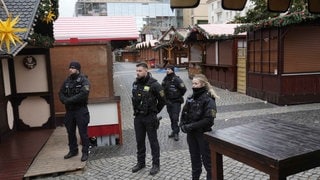 Polizisten stehen Wache an einem Weihnachtsmarkt in Magdeburg.