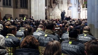 Feuerwehrleute sitzen im Gedenkgottesdienst an den Anschlag in Magdeburg.