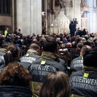 Feuerwehrleute sitzen im Gedenkgottesdienst an den Anschlag in Magdeburg.