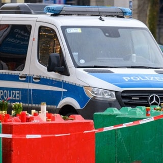 Ein Wagen der Polizei steht vor Betonabsperrungen des Weihnachtsmarkts in Magdeburg.