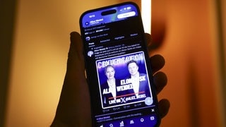 Ein Smartphone mit der Ankündigung eines Gesprächs zwsichen Elon Musk und Alice Weidel