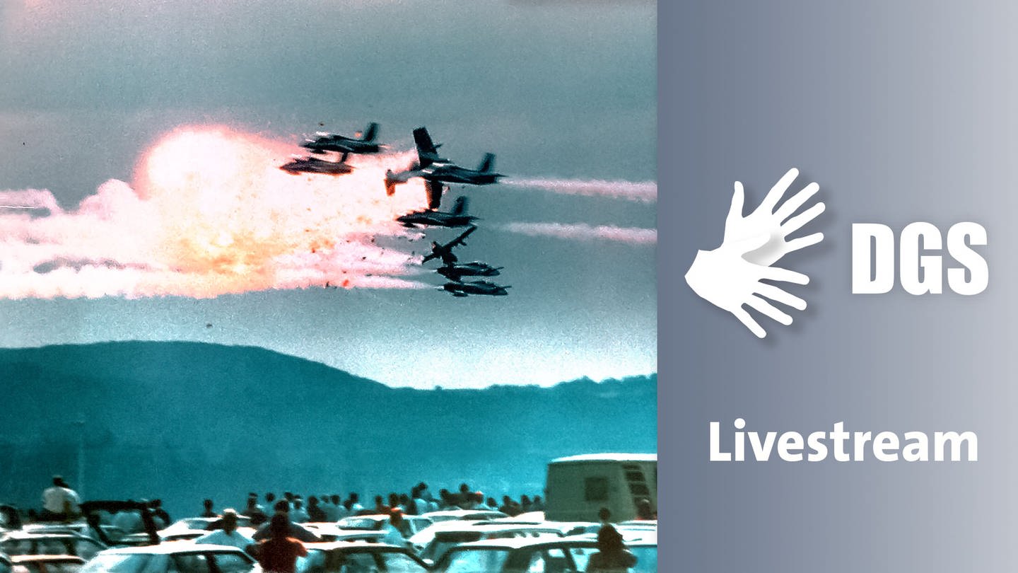Viele Zuschauer:innen inmitten von Autos schauen am US-Luftwaffenstützpunkt Ramstein 1988 in den Himmel, wo Flugzeuge eines italienischen Kunstflugteams kollidieren.