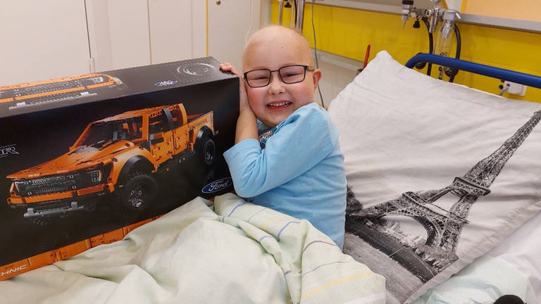 Der an Leukämie erkrankte Vincent im Krankenhausbett. In seiner Hand hält er ein großes Lego Paket. 