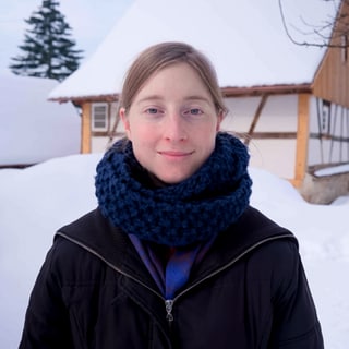 Stefanie setzt sich im Verein taxmenow für Steuergerechtigkeit ein. Stefanie steht vor einem Haus in einer Winterlandschaft. Sie schaut mit direktem Blick in die Kamera.