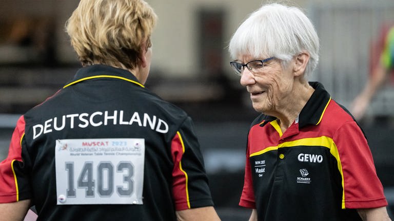 Seniorin Heidi beim Tischtennis- Spiel um Platz 1 im Doppel. Links daneben ist auf dem Rücken der Spielpartnerin der Schriftzug ‚Deutschland‘ zu lesen. 