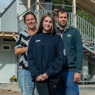 Familie aus Mutter, Vater und Tochter vor ihrem Wohncontainer