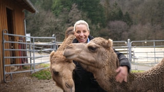 Annika liebt Dromedare. Sie und ihr Dromedar Khaled schauen in die Kamera. 