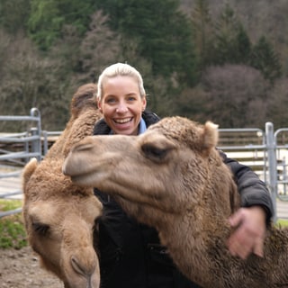 Annika liebt Dromedare. Sie und ihr Dromedar Khaled schauen in die Kamera. 