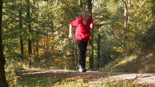 Senior in roter Jacke rennt durch den Wald