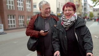 Jutta und Kurt lachen gemeinsam in Karlsruhe. Er lacht seine Jugendliebe an.