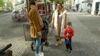 Valentina steht mit ihrem Sohn Joschua in der Karlsruher Innenstadt und unterhält sich mit Tici, die ein Mikro in der Hand hält.  