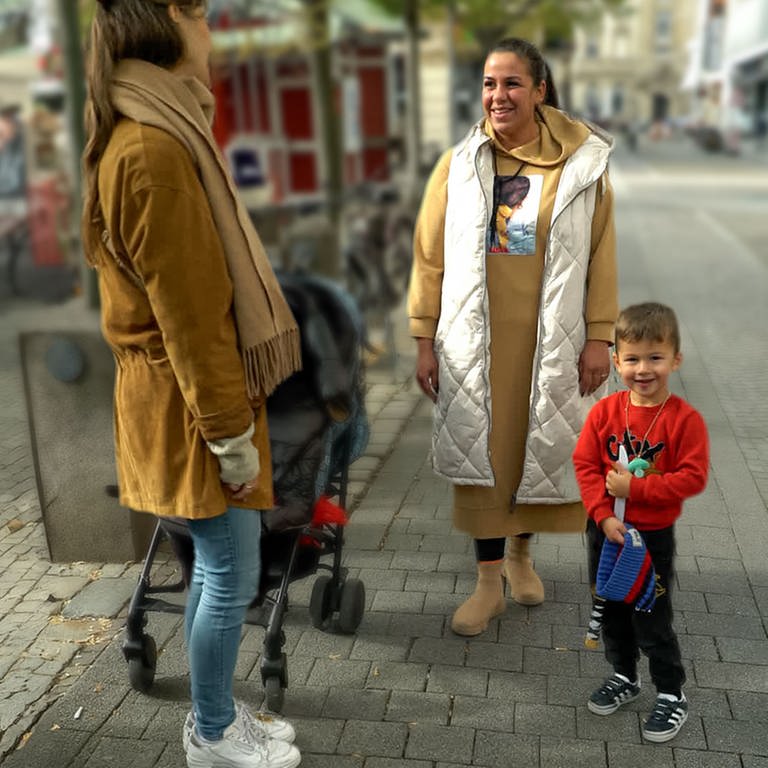 Valentina steht mit ihrem Sohn Joschua in der Karlsruher Innenstadt und unterhält sich mit Tici, die ein Mikro in der Hand hält.  