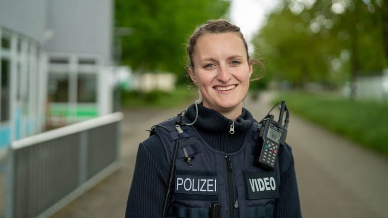 Eine junge Frau namens Lara lächelt in ihrer Polizeiuniform. 