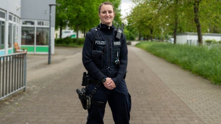 Ganzkörperfoto von Polizistin Lara in ihrer Uniform vor ihrem Büro. 