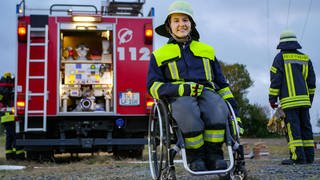 Junge Frau im Rollstuhl vor Feuerwehrauto