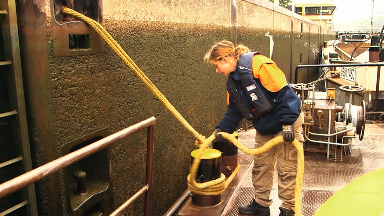 Junge Binnenschifferin vertäut das Kranschiff in einer Schleuse