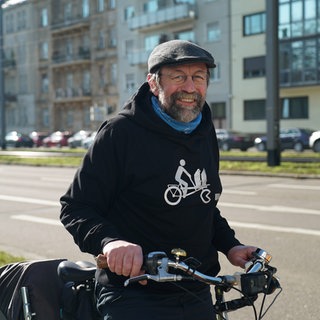 Älterer Herr auf dem Fahrrad. Im Hintergrund das Mannheimer Schloss.