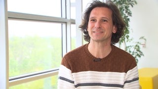 Ein Mann mit braunen Haaren am Fenster sitzend