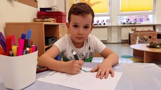 Julian malt im Kindergarten ein Bild mit einem rot-grünen Stern darauf.