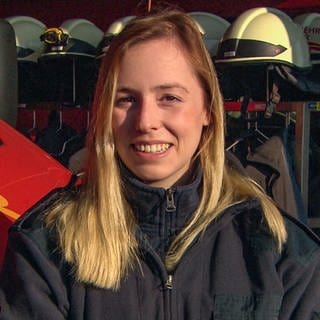 Feuerwehrfrau Selina, jung, 22 Jahre, vor einem Feuerwehrauto