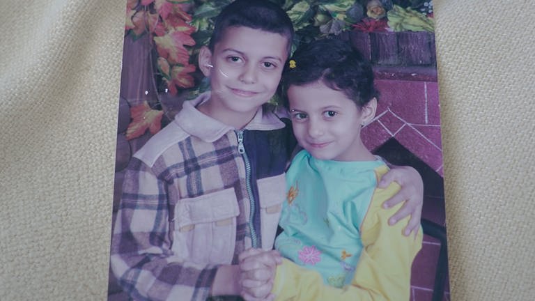 Zwei Kinder im Grundschulalter halten sich im Arm: Maya und ihr Bruder in Syrien