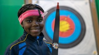 Gabriella (10) mit ihrem Bogen vor der Zielscheibe