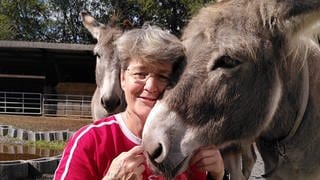 Ältere Frau in roten T-Shirt mit Esel im Arm