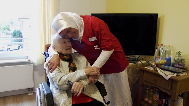 Altenpflegerin lacht zusammen mit Seniorin in Zimmer in Altenheim.