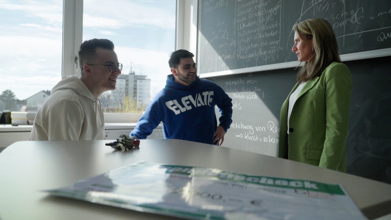 Zwei junge Männer mit Lehrerin in Klassenzimmer.