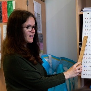 Mitteljunge Lehrerin vor deutschem Alphabet.