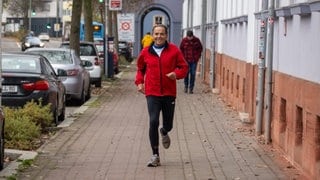 Älterer Herr joggend auf Gehweg