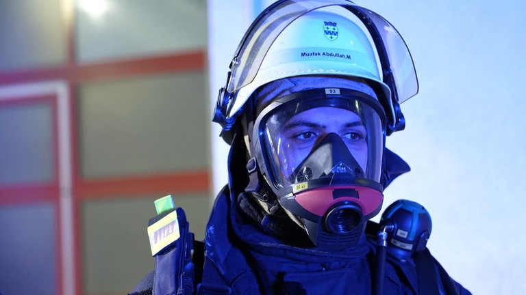 Ein Mann mit Feuerwehrhelm wird von blauem Licht angeleuchtet.