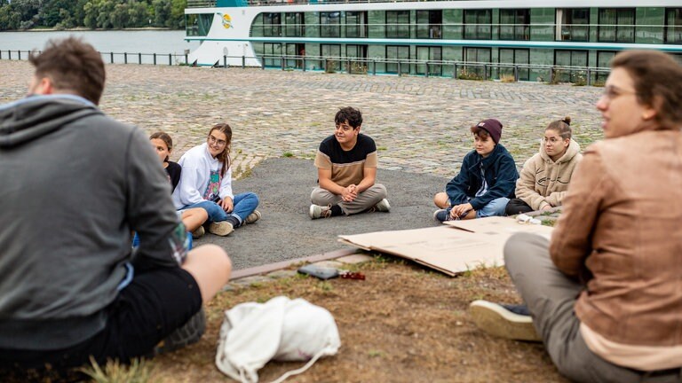 Jungen Menschen im Sitzkreis am Rheinufer