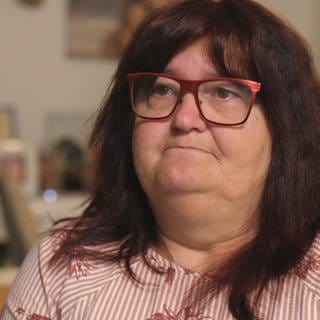 Heike Frohnhöfer, eine Frau mit dunkelroten Haaren und Brille, blickt traurig von der rechten in die linke Bildhälfte