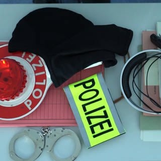 Polizeiausrüstung: Handschelle, Kelle, Funkgerät und Akten liegen auf einem Tisch