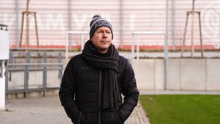 Mann mit Sport-Mütze läuft durch Fußballstadion