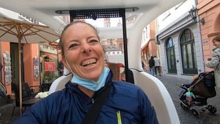 Daiana Neher sitzt in ihrer Fahrrad-Rikscha und lacht während sie durch die Mainzer Altstadt fährt