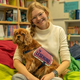 Junge Frau mit ihrem Hund auf dem Schoß 