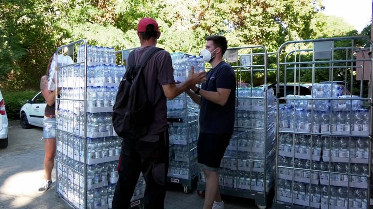 Zwei Menschen vor Rollcontainern mit Wasserflaschen
