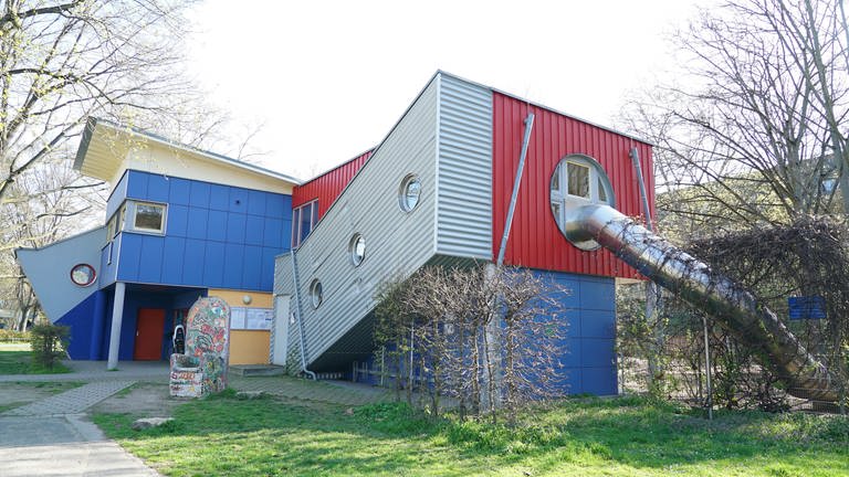 Außenaufnahme eines Gebäudes mit roten, blauen und grauen Wänden.