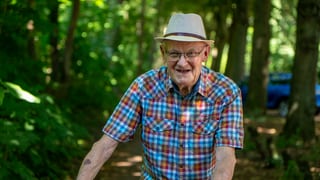 Älterer Herr mit Hut und kariertem Hemd im Wald