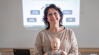 Frau mit braunen Haaren und Brille im gestreiften T-Shirt lächelt in Kamera.