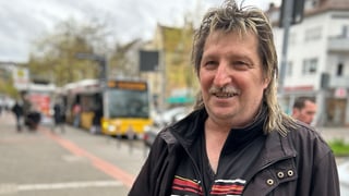 Michael steht in Bad Cannstatt mit Blumen und einer Topfpflanze in der Hand. Er lächelt in die Kamera. Im Hintergrund ist der Stuttgarter Verkehr zu sehen.