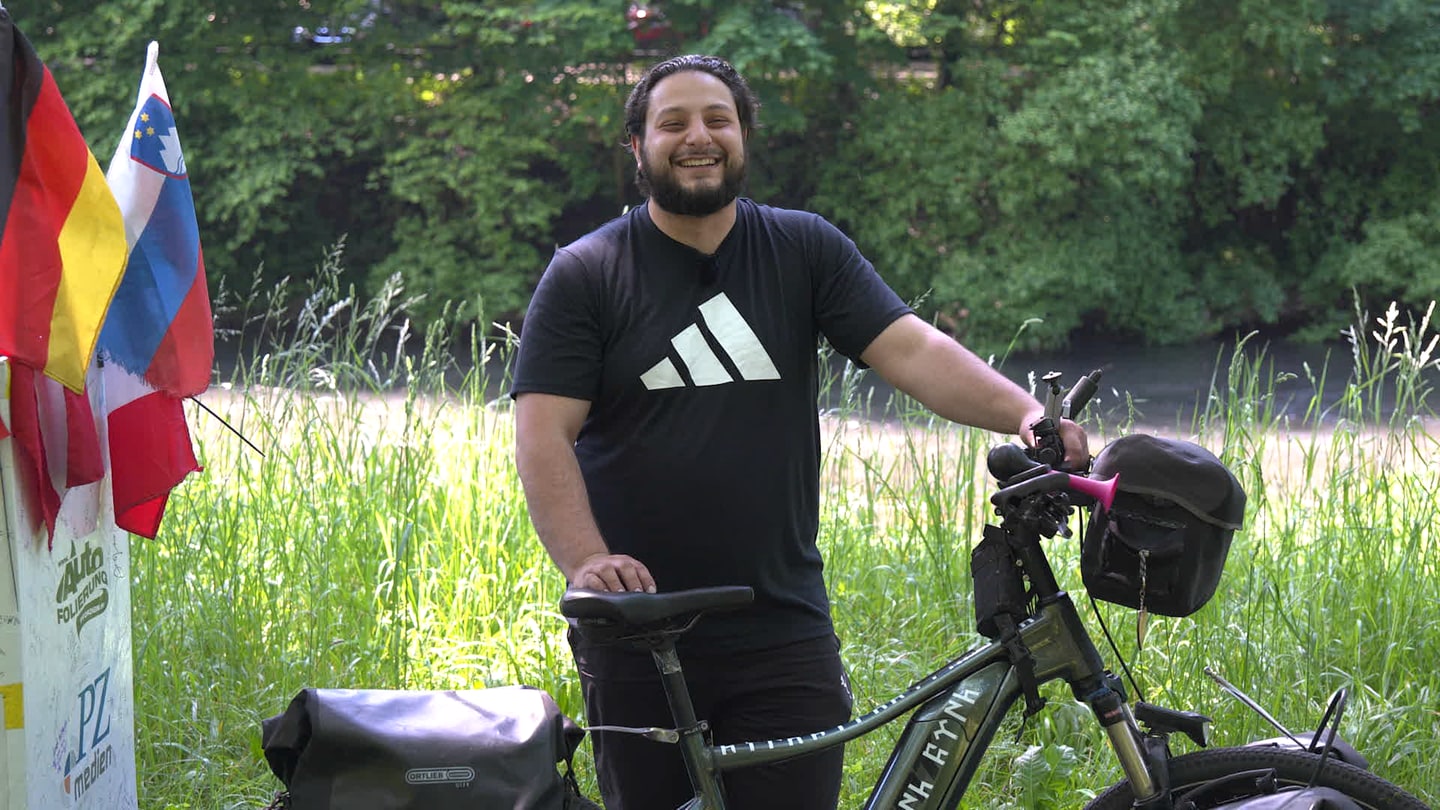 Burak lehnt an seinem Fahrrad. Er ist von Deutschland in die Türkei gefahren und erzählt von seinen Erlebnissen.