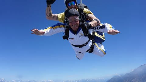 Cedric verbringt gerne Zeit mit seinem Opa Gery. Gery macht einen Fallschirmsprung. Gery ist bei einem Tandemsprung im Fall und lacht in die Kamera. 